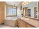 Bathroom with corner soaking tub, window view, and neutral-toned vanity at 3192 Taylor St, Logandale, NV 89021