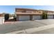 Exterior view of home featuring multiple garages with brick accents and mature trees, creating curb appeal at 3484 Nightflower Ln # B, Las Vegas, NV 89121