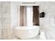 Modern bathroom featuring a standalone tub with marble walls, stool, and elegant fixtures at 4381 W Flamingo Rd # 5708, Las Vegas, NV 89103