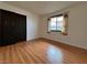 Bedroom featuring wood-look floors, white walls, a window with patterned curtains and closet with dark door at 6216 Bullion Blvd, Las Vegas, NV 89103