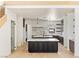 Open-concept kitchen featuring double islands with countertops with marble-look veining, modern pendant lighting, and light wood floors at 6383 Horse Dr, Las Vegas, NV 89131