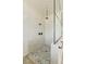 Modern shower featuring pebble flooring, white tiled walls, black fixtures, and glass enclosure at 6383 Horse Dr, Las Vegas, NV 89131