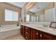 Bathroom with a double sink vanity, soaking tub, and large mirror with natural light at 6816 Royal Poinciana Ct, Las Vegas, NV 89131