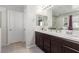 Well-lit bathroom featuring double sinks, dark wood cabinetry and a large mirror at 7884 Patagonia Point Ct, Las Vegas, NV 89179
