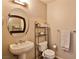 Cozy bathroom featuring a pedestal sink, oval mirror, and convenient shelving unit for towel and toiletry storage at 8255 Las Vegas Blvd # 313, Las Vegas, NV 89123