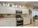 Well-lit kitchen showcasing a stainless steel range, microwave, and white cabinets at 10217 Queens Church Ave, Las Vegas, NV 89135