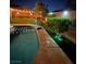 Sparkling pool with lush landscaping, mature trees, and night lighting at 10662 Bonchester Hill St, Las Vegas, NV 89141