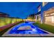 This backyard features a luxurious pool with a bar, a spa and artificial grass and lighting for evening enjoyment at 10748 Steel Ridge Ct, Las Vegas, NV 89135