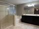 Bright bathroom featuring a glass-enclosed shower, soaking tub, double vanity with dark cabinets, and tile floors at 10941 Prudhoe Bay St, Las Vegas, NV 89179