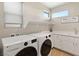 Well-lit laundry room featuring a new washer and dryer, storage cabinets, and sleek countertop space at 11943 Rockview Point St, Las Vegas, NV 89138