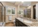 Well-lit bathroom with double sinks with granite countertop, seamless glass shower and custom shutters at 12 Wade Hampton Trl, Henderson, NV 89052