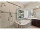 Modern bathroom featuring seamless glass shower, soaking tub with view to yard, and stylish fixtures at 12 Wade Hampton Trl, Henderson, NV 89052