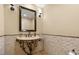 Elegant powder room featuring mosaic tile accent wall, ornate pedestal sink, and decorative sconces at 12 Wade Hampton Trl, Henderson, NV 89052