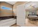 A bathroom featuring a soaking tub and view of the main bedroom with ceiling fan at 1455 Waterfall Ln, Mesquite, NV 89034