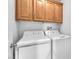 A laundry room featuring a stacked washer and dryer and wooden cabinets above at 2526 Begonia Valley Ave, Henderson, NV 89074