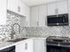 Kitchen sink with stainless steel faucet, dark countertop and mosaic tile backsplash at 2720 Beaver Creek Ct # 202, Las Vegas, NV 89117