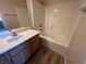 Bathroom featuring a vanity, shower-tub combo with white tile, and wood-look flooring at 3118 Honeysuckle Ave, North Las Vegas, NV 89031