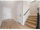 Entryway with wooden floors, stairs with black metal handrails, a coat closet, and a white interior door at 350 Robledo St, Las Vegas, NV 89138