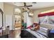 Bright bedroom featuring a ceiling fan, mounted TV, red chaise lounge, and ensuite bathroom entrance at 3805 Sorrowing Sparrow Ct, North Las Vegas, NV 89032