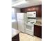 Kitchen with white appliances, brown cabinets, and granite countertops at 4965 Indian River Dr # 101, Las Vegas, NV 89103