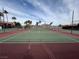 Outdoor tennis court featuring green and red surfaces and surrounded by fencing and lush palm trees at 4965 Indian River Dr # 101, Las Vegas, NV 89103