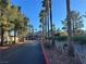 Scenic drive to community entrance with wrought iron gates, mature trees, and landscaping at 5055 W Hacienda Ave # 1116, Las Vegas, NV 89118