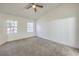 Light-filled main bedroom featuring carpet floors, ceiling fan and two windows at 5216 Las Cruces Dr, Las Vegas, NV 89130