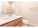 A well lit bathroom featuring a cherry wood vanity, a sink and a toilet at 639 Grey Saker St, Las Vegas, NV 89138