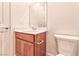 A well lit bathroom featuring a cherry wood vanity, a sink and a toilet with modern fixtures at 639 Grey Saker St, Las Vegas, NV 89138