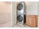 This laundry area features stacked appliances next to a wooden cabinet and sink, blending functionality with practical design at 639 Grey Saker St, Las Vegas, NV 89138