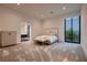 Bright main bedroom with a sleek upholstered bed, modern dresser, and sliding glass doors to a garden at 678 Blackrock Rim Dr, Henderson, NV 89012