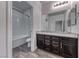 Bathroom with dark wood vanity, granite counters, wood-look tile floors and shower-over-tub with tile surround at 7106 Stanley Frederick St, Las Vegas, NV 89166