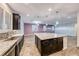 Spacious kitchen with a large island, dark wood cabinets, stainless steel sink, granite counters and tiled flooring at 7106 Stanley Frederick St, Las Vegas, NV 89166