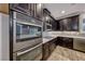 Close-up of the kitchen features stainless steel appliances, dark cabinets, granite countertops, and decorative backsplash at 7106 Stanley Frederick St, Las Vegas, NV 89166