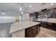 Open kitchen with dark wood cabinets, stainless appliances, an island with granite countertop, and wood-look tile floors at 7106 Stanley Frederick St, Las Vegas, NV 89166