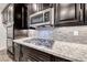 Close-up of the stainless gas stovetop and microwave are set against dark cabinets and granite countertops at 7106 Stanley Frederick St, Las Vegas, NV 89166