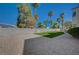 Backyard with artificial turf, rock bed, palm trees, and brick privacy fence at 7650 Hartwell Dr, Las Vegas, NV 89123