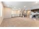 Open-concept living area with plush carpeting, a modern fireplace, neutral paint, and an adjacent kitchen and staircase at 8012 Carpenter Creek Ave, Las Vegas, NV 89113