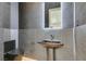 Modern powder room featuring geometric tile walls, a sleek pedestal sink, and a black toilet at 8649 Robinson Ridge Dr, Las Vegas, NV 89117