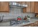 Close up of a gourmet kitchen featuring a gas cooktop and a stylish tile backsplash at 10233 Madison Grove Ave, Las Vegas, NV 89166