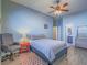 This cozy bedroom features a ceiling fan, wood-look tile flooring, and a chair with a red end table at 10446 Abbotsbury Dr, Las Vegas, NV 89135