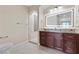 Bright bathroom with dark wood vanity, lighted mirror, and step-in shower at 16 Via Visione # 101, Henderson, NV 89011