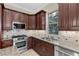 Close-up of stainless gas cooktop and sink with granite countertops and modern cabinetry at 16 Via Visione # 101, Henderson, NV 89011