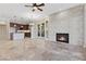 Spacious living room featuring a stacked stone fireplace, tile floors, ceiling fan and view to the kitchen at 16 Via Visione # 101, Henderson, NV 89011