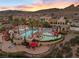 An aerial shot shows a community pool with several red awnings, lush landscaping, and mountain views at 16 Via Visione # 101, Henderson, NV 89011