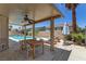 Covered outdoor patio with ceiling fan, dining table, and lounge chairs near pool at 1754 Quiver Point Ave, Henderson, NV 89012