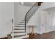 Curved staircase with wood and iron detailing leading to the upper level, a bright accent table, and a white door at 1754 Quiver Point Ave, Henderson, NV 89012