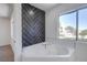 Corner bathtub with dark accent tile wall complemented by natural light from a nearby window at 2032 Jesse Scott St, Las Vegas, NV 89106