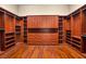 A large walk-in closet has custom shelves, drawers, cabinets, and hardwood floors at 32 Hunting Horn Dr, Las Vegas, NV 89135