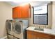 Efficient laundry room equipped with modern front-load washer and dryer, storage cabinets, and a sink for convenience at 32 Hunting Horn Dr, Las Vegas, NV 89135